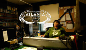 Screen capture from Radio Bingo, depicting the radio station's Bingo caller in her radio booth