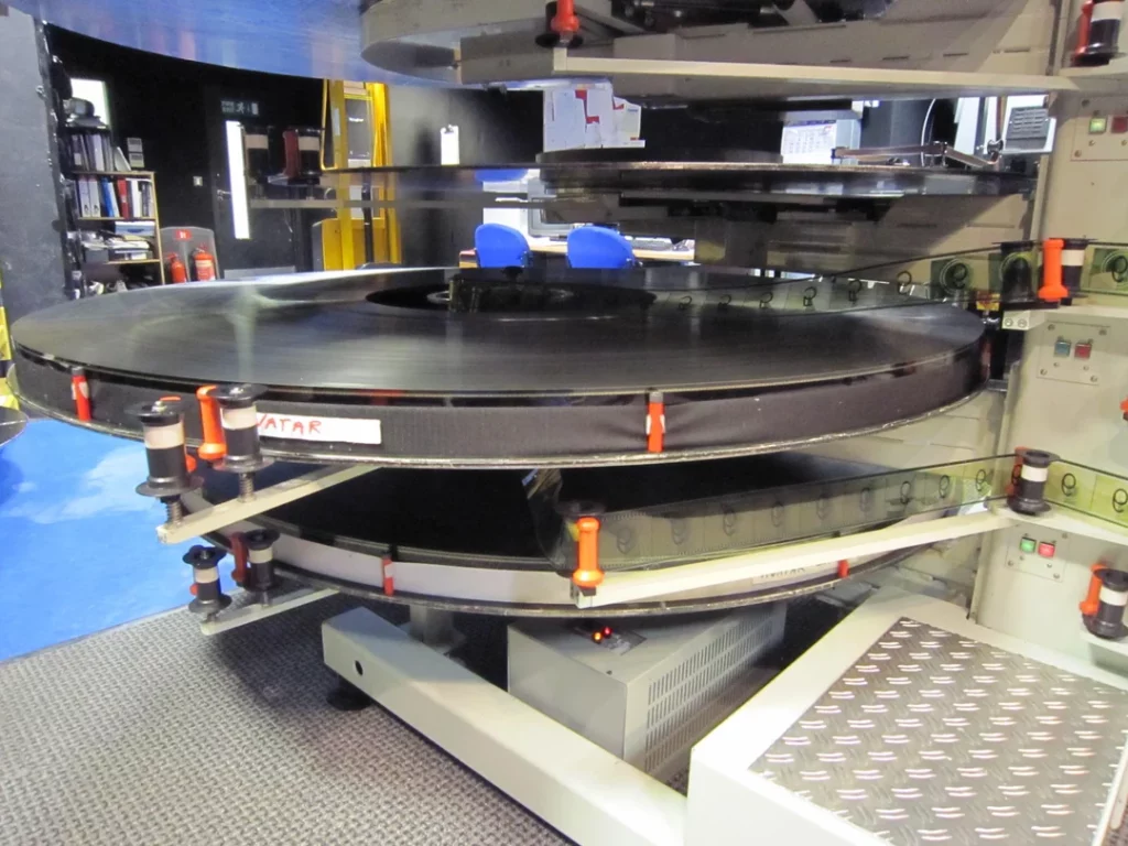 Image of projectionist room showcasing the enormous size of an IMAX 70mm film reel. 